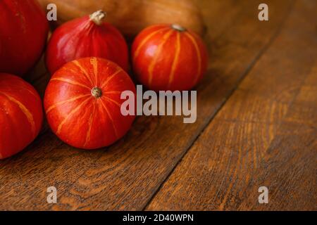 Une couche plate de petits citrouilles hokkaido rouges se trouve sur le plancher en bois. Décorations d'Halloween. Copier l'espace. Carte postale pour les vacances. Légumes frais d'automne Banque D'Images