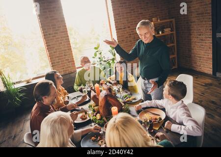 Photo de la famille complète rassemblant huit personnes un homme oncle stand agitant les mains sourire dire curieux occasion intéressante dîner servi grande table turquie Banque D'Images