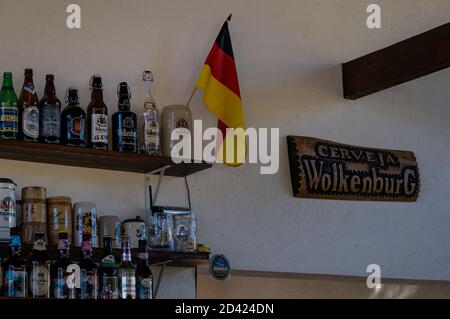 Le mur décoré de la salle à manger de la brasserie Wolkenburg avec quelques bouteilles de bière sur les étagères avec le drapeau allemand et une assiette en bois. Banque D'Images
