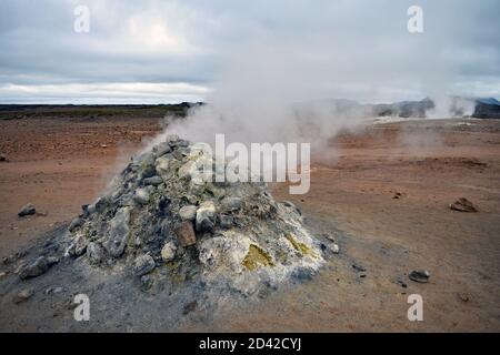 Le Smoker Sulfurique dans la zone géothermique de Hverir près du lac Myvatn, dans le nord de l'Islande. De la vapeur s'échappe des évents à vapeur dans un paysage de couleur orange. Banque D'Images
