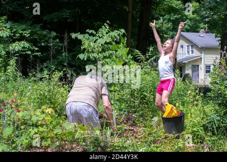 Grandpa plante un nouvel arbre de bourgeon rouge pour le jour de la terre, et sa petite fille partenaire commande les pouvoirs d'être pour le faire pousser Banque D'Images