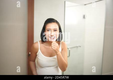 Portrait de jeune femme enceinte se brosser les dents à bains Banque D'Images