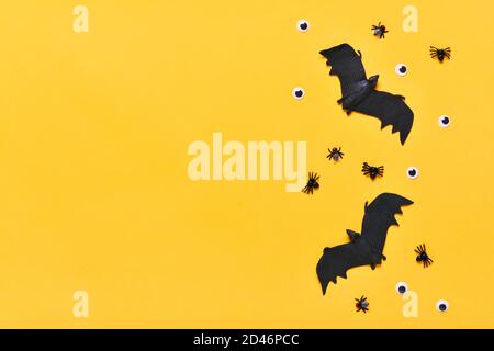 Araignées et mouches noires, yeux et chauve-souris à l'intérieur sur fond jaune vue du dessus Flat Lay Happy Halloween Creative concept carte de vacances Mock up Banque D'Images