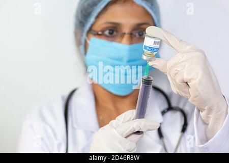 Un médecin indien tire un médicament dans une seringue d'injection à partir d'un flacon de vaccin Banque D'Images