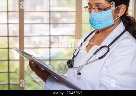 Femme indienne médecin portant un stéthoscope examiner un rapport médical dans une clinique de santé Banque D'Images