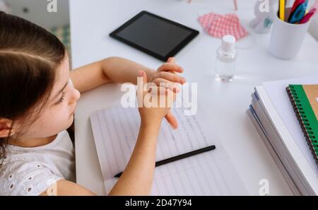 Fille appliquant un désinfectant pour les mains pendant ses devoirs Banque D'Images