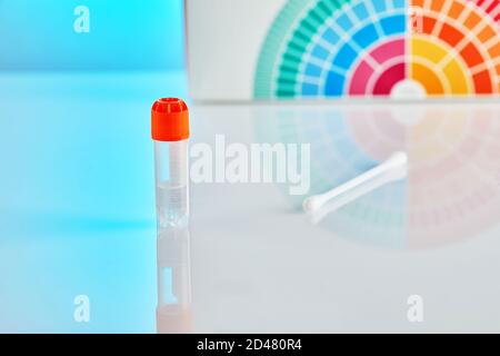 Un tube à essai avec un liquide pour l'analyse de l'ADN et un bâton contre le fond d'une boîte avec un set pour le test, sur un fond bleu avec réflexion. D Banque D'Images