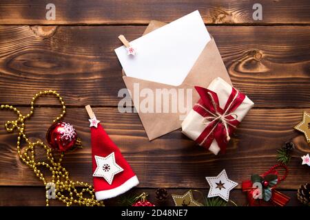 Enveloppe postale en papier artisanal avec une feuille blanche pour le texte sur fond de bois avec décoration de Noël. Une lettre au Père Noël, une liste de souhaits, une nouvelle Banque D'Images