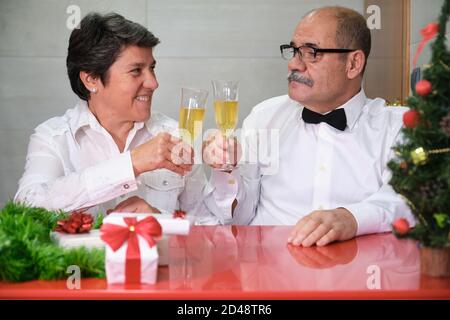 Couple senior célébrant des coupes de champagne à champagne de noël. Concept de fête de Noël. Banque D'Images