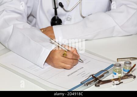 Une femme médecin rédigeant un formulaire de prescription médicale avec des flacons de vaccin sur la table Banque D'Images