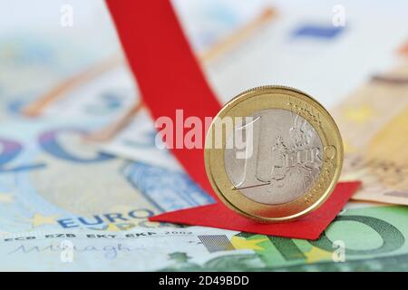 Pièce en euros avec flèche rouge décroissante sur les billets en euros - Concept de diminution de la valeur en euros et de perte de monnaie Banque D'Images