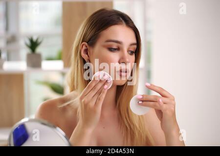 Concept de soin de la peau, portrait de la femme heureuse appliquant de la crème cosmétique sur le visage. Banque D'Images