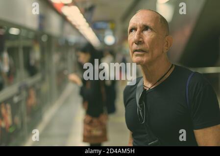 Senior homme chauve touristique pensée lors de l'attente à l'intérieur de la gare de métro de Bangkok Thaïlande Banque D'Images