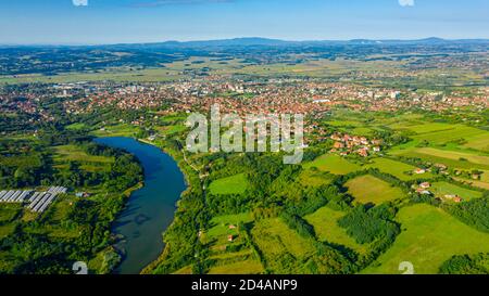 Tourné au-dessus de vert paysage vallonné avec le lac, plusieurs parcelles cultivées parmi les arbres forestiers et la ville au loin. Banque D'Images