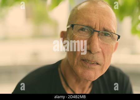 Visage de l'homme tourisme senior chauve portant des lunettes tout en vous relaxant sous l'arbre dans la ville Banque D'Images