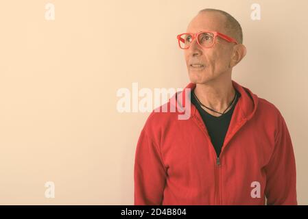 Studio shot of bald man pense tout en portant des lunettes contre fond blanc Banque D'Images