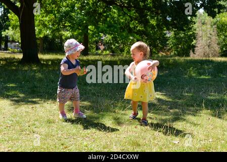 Deux petits enfants jouant dans un parc avec une balle Banque D'Images