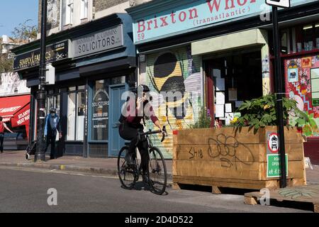 Une cycliste féminine utilisant un téléphone portable tout en faisant un vélo sur la fermeture de la route Atlantique le 16 septembre 2020 à Brixton au Royaume-Uni. P Banque D'Images