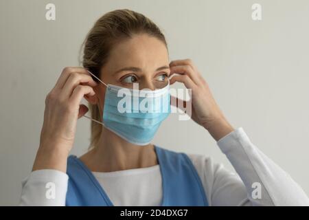 Une travailleuse de la santé portant un masque sur fond blanc Banque D'Images