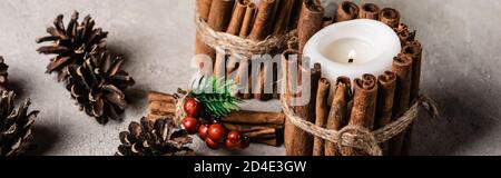 Photo panoramique de bougies décorées avec des bâtons de cannelle près du pin cônes Banque D'Images