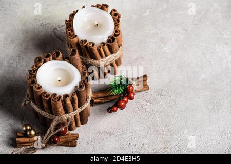 Bougies parfumées décorées de bâtons de cannelle sur fond gris et texturé arrière-plan Banque D'Images