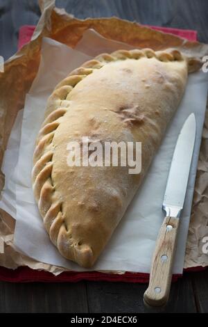 Pizza italienne calzone aux champignons, épinards et fromage sur une surface en bois, style rustique, sélectif Banque D'Images