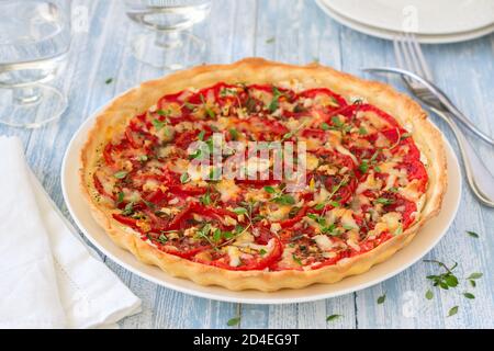 Délicieuse tarte aux tomates avec du fromage de chèvre, du thym et de l'ail sur une table en bois bleu Banque D'Images