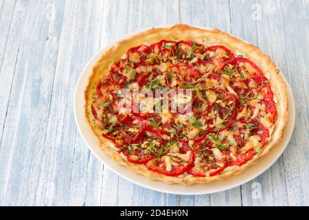 Délicieuse tarte aux tomates avec du fromage de chèvre, du thym et de l'ail sur une table en bois bleu Banque D'Images