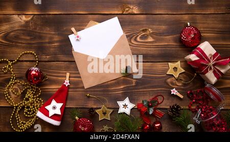 Enveloppe postale en papier artisanal avec une feuille blanche pour le texte sur fond de bois avec décoration de Noël. Une lettre au Père Noël, une liste de souhaits, une nouvelle Banque D'Images