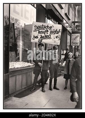 Allemagne des années 1930 propagande antisémite du boycott antisémite nazi 1er avril 1933 Vintage d'avant-guerre une étiquette incendiaire raciste grossière antisémite avec des « goons » souriants du NSDAP "Les Allemands n'achètent pas aux Juifs" en dehors d'une entreprise appartenant à des Juifs. Le gouvernement nazi a organisé un boycott d'une journée de toutes les entreprises juives en Allemagne, avec l'aide de Julius Streicher, éditeur du quotidien antisémite Der Sturmer. Le boycott n'a pas réussi à attirer le soutien de l'opinion publique. Quelques jours plus tard, des lois ont été proclamées pour retirer les juifs allemands de diverses professions. Banque D'Images