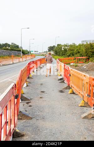 Femme piétonne traversant les travaux de la route de Sallins près de Johnstown dans le comté de Kildare, en Irlande Banque D'Images