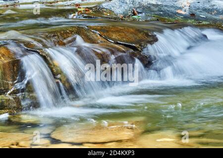 flux clair sur les pierres, formant une petite cascade, les jets d'eau sont flous en mouvement Banque D'Images