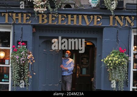 Un homme ferme l'auberge Beehive dans le Grassmarket, Édimbourg, alors que des restrictions temporaires annoncées par le premier ministre Nicola Sturgeon pour aider à freiner la propagation du coronavirus sont entrées en vigueur vendredi à partir de 18 heures. Banque D'Images