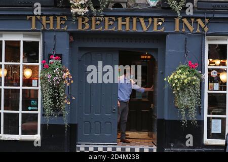 Un homme ferme l'auberge Beehive dans le Grassmarket, Édimbourg, alors que des restrictions temporaires annoncées par le premier ministre Nicola Sturgeon pour aider à freiner la propagation du coronavirus sont entrées en vigueur vendredi à partir de 18 heures. Banque D'Images