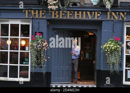 Un homme ferme l'auberge Beehive dans le Grassmarket, Édimbourg, alors que des restrictions temporaires annoncées par le premier ministre Nicola Sturgeon pour aider à freiner la propagation du coronavirus sont entrées en vigueur vendredi à partir de 18 heures. Banque D'Images