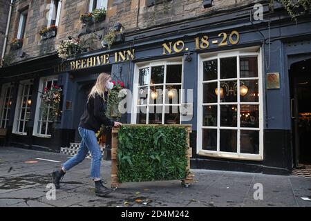 Les gens s'éloignent de l'hôtel Beehive Inn dans le Grassmarket, à Édimbourg, alors que les restrictions temporaires annoncées par le premier ministre Nicola Sturgeon pour aider à freiner la propagation du coronavirus sont entrées en vigueur vendredi à partir de 18 heures. Banque D'Images