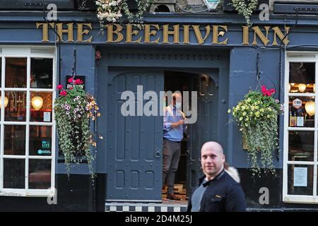 Un homme ferme l'auberge Beehive dans le Grassmarket, Édimbourg, alors que des restrictions temporaires annoncées par le premier ministre Nicola Sturgeon pour aider à freiner la propagation du coronavirus sont entrées en vigueur vendredi à partir de 18 heures. Banque D'Images