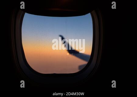 vue de la fenêtre de l'avion pendant le vol de l'aile au coucher du soleil Banque D'Images