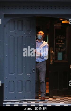 Un homme ferme l'auberge Beehive dans le Grassmarket, Édimbourg, alors que des restrictions temporaires annoncées par le premier ministre Nicola Sturgeon pour aider à freiner la propagation du coronavirus sont entrées en vigueur vendredi à partir de 18 heures. Banque D'Images