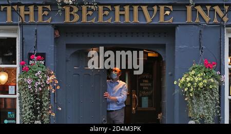 Un homme ferme l'auberge Beehive dans le Grassmarket, Édimbourg, alors que des restrictions temporaires annoncées par le premier ministre Nicola Sturgeon pour aider à freiner la propagation du coronavirus sont entrées en vigueur vendredi à partir de 18 heures. Banque D'Images