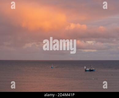 Lyme Regis, Dorset, Royaume-Uni. 9 octobre 2020. Météo au Royaume-Uni: Un bateau retourne au port comme le ciel brille avec la couleur du coucher du soleil à Lyme Regis. Credit: Celia McMahon/Alamy Live News Banque D'Images