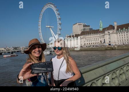 Femme prenant des selfies avec le London Eye et le County Hall Bâtiment en arrière-plan le 14 septembre 2020 La Banque du Sud au Royaume-Uni Banque D'Images