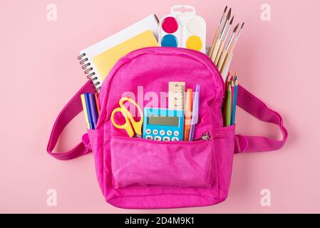 Concept de retour à l'école. Étudier le concept. Haut au-dessus de la vue de la tête photo de sac à dos rose et de papeterie colorée isolée sur fond rose pastel Banque D'Images
