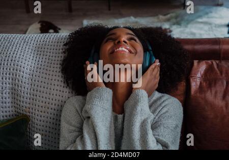 Belle jeune femme heureux d'écouter de la musique sur les écouteurs dans le salon Banque D'Images