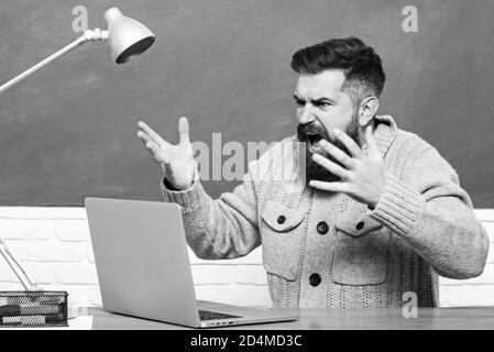 Tuteur. Jeune enseignant près du tableau noir dans la salle de classe de l'école. Journée des enseignants. Professeur barbu en classe d'éducation près de Blackboard. Banque D'Images