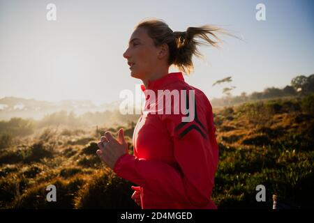 Athlète féminine en action, en plein air sur la piste dans la forêt terrestre. Banque D'Images