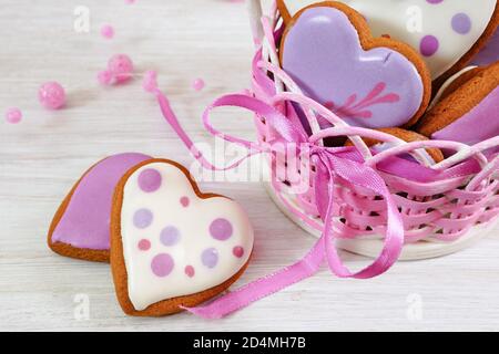 Biscuits au pain d'épice dans un panier en osier. Biscuits de pain d'épice multicolores faits à la main en forme de coeur sur une table blanche Banque D'Images