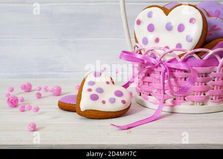 Biscuits au pain d'épice dans un panier en osier. Biscuits de pain d'épice multicolores faits à la main en forme de coeur sur une table blanche. Gros plan Banque D'Images