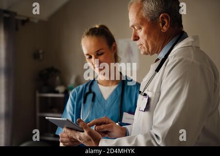 Discussion entre les médecins masculins et féminins sur la tablette numérique Banque D'Images