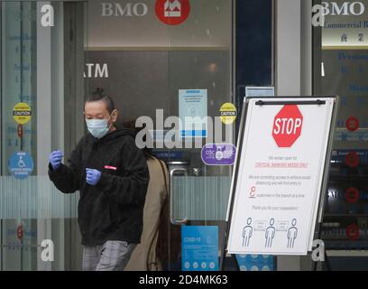 Vancouver, Canada. 9 octobre 2020. Une personne portant un masque facial et des gants quitte une banque à Vancouver (Colombie-Britannique), Canada, le 9 octobre 2020. Selon un nouveau rapport de modélisation COVID-19 publié vendredi par le gouvernement canadien. Au total, le COVID-19 canadien est en voie de toucher entre 188,150 et 197,830 cas et entre 9,690 et 9,800 décès en date du 17 octobre. Au vendredi midi, il y avait au total 177,613 cas de COVID-19 et 9,583 décès, selon CTV. Credit: Liang Sen/Xinhua/Alay Live News Banque D'Images